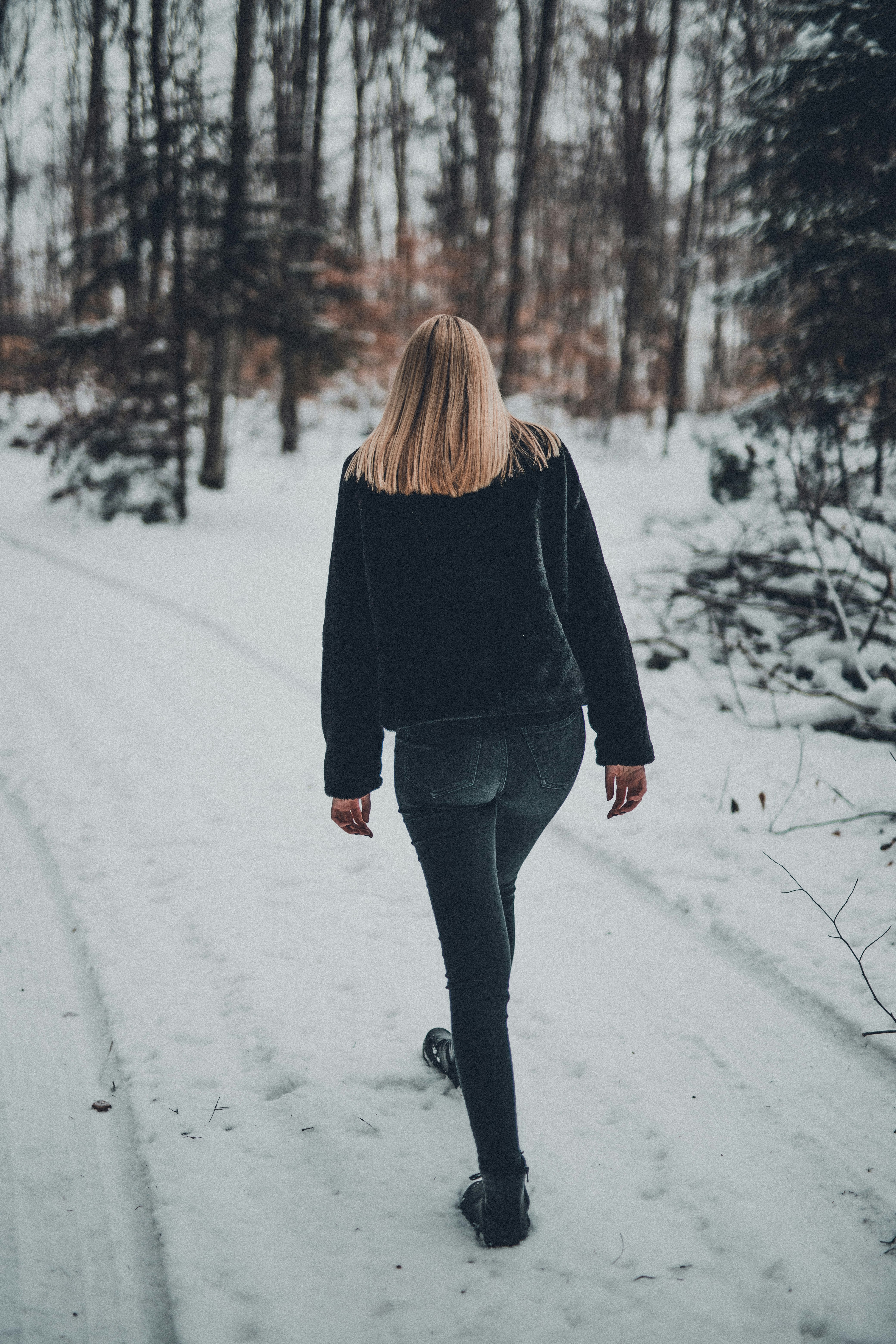 woman in black long sleeve shirt and blue denim jeans standing on snow covered ground during